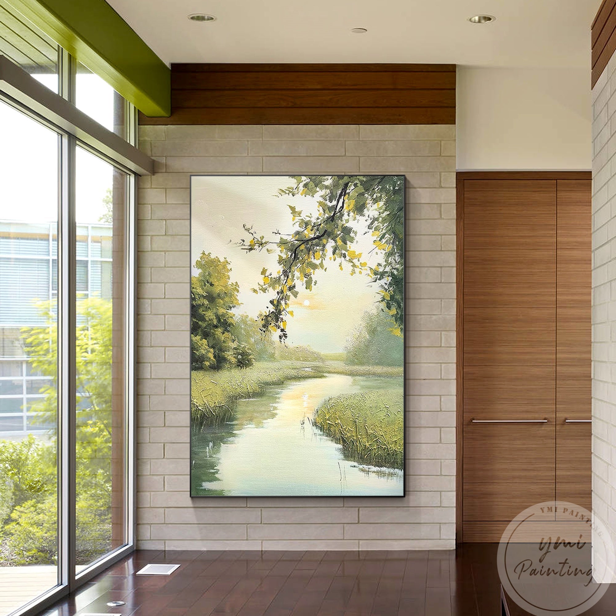 This tranquil painting of a riverside scene features verdant fields and soft yellow spring light, perfect for the space next to French window.
