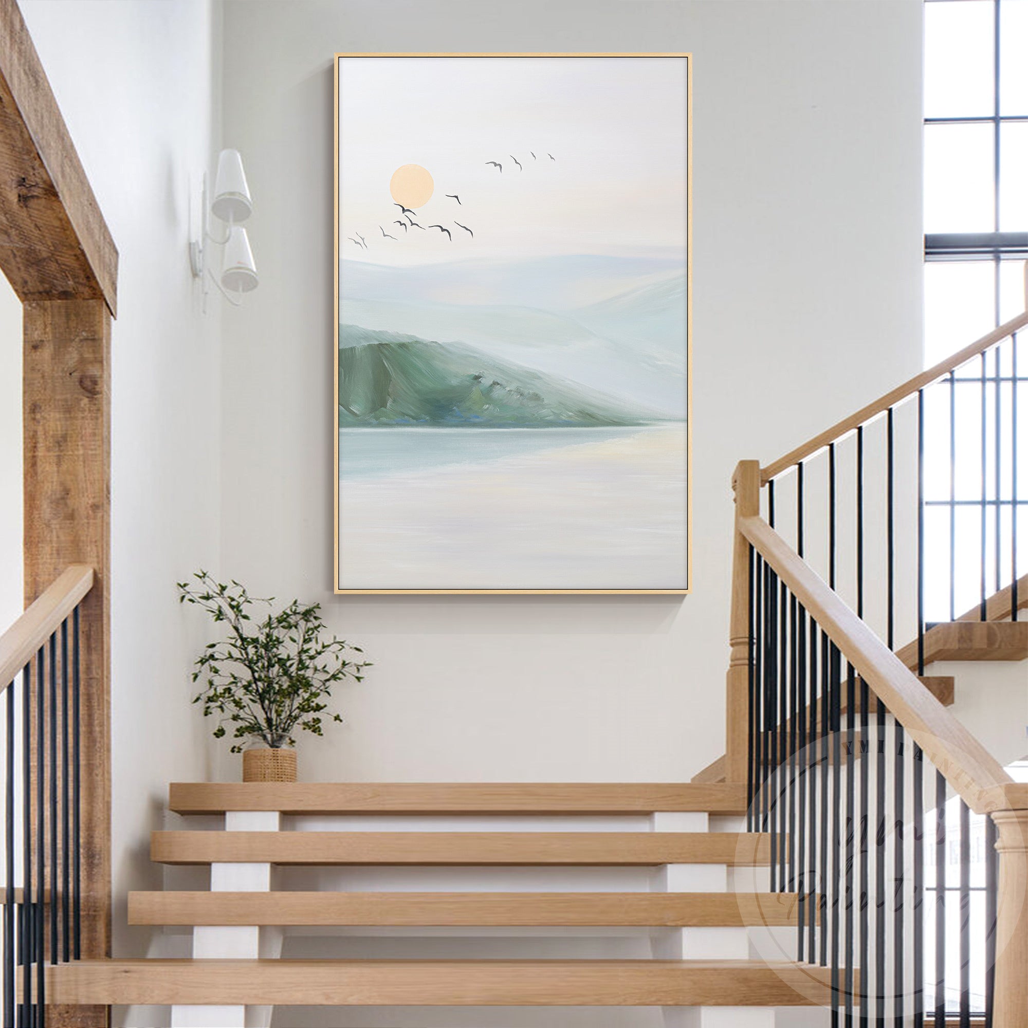 Peaceful sunset over mountains with water reflections and silhouetted birds in the fading horizon painting hanging on the wall next to stairs.